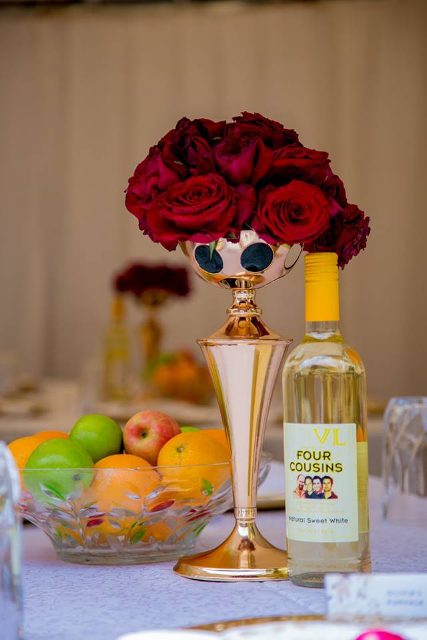 A gold centerpiece with red roses Blessed HANDS DECOR Services